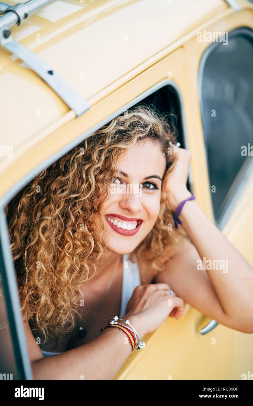Portrait of happy blonde woman looking out de la fenêtre de voiture classique Banque D'Images