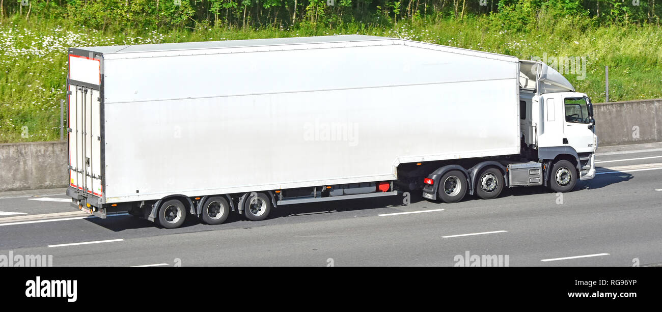 Et côté vue arrière de forme aérodynamique de long plain white nettoyer sans marque camion livraison poids lourds Truck & Trailer articulés roulant le long de la route autoroute britannique Banque D'Images