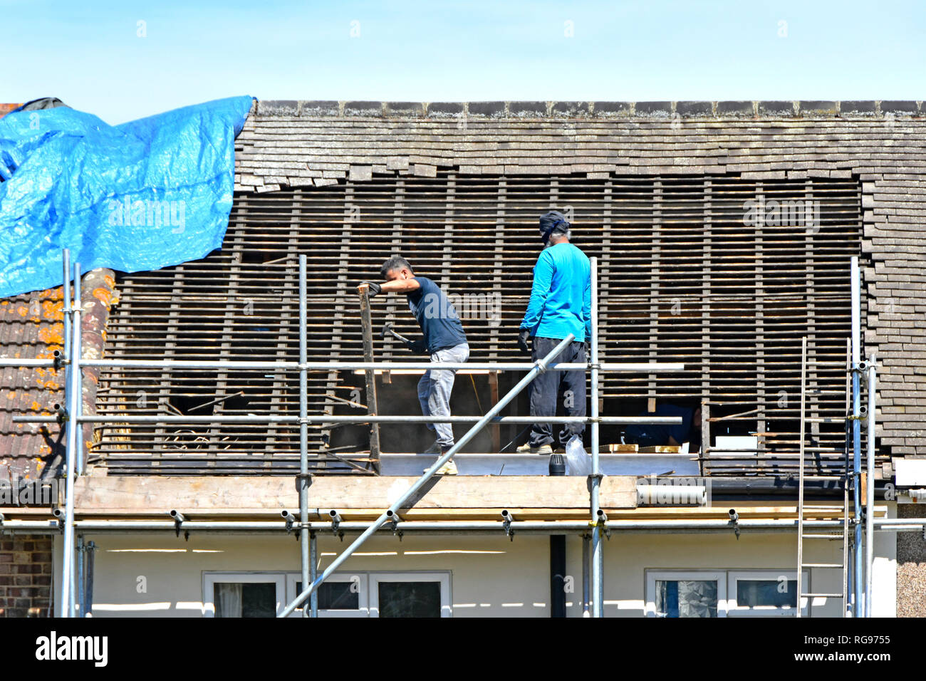 Les travailleurs du constructeur sur les échafaudages de la dépose des tuiles du toit et bois dans la préparation de nouveaux chambre mansardée dormer dans loft de maison mitoyenne en Romford East London UK Banque D'Images