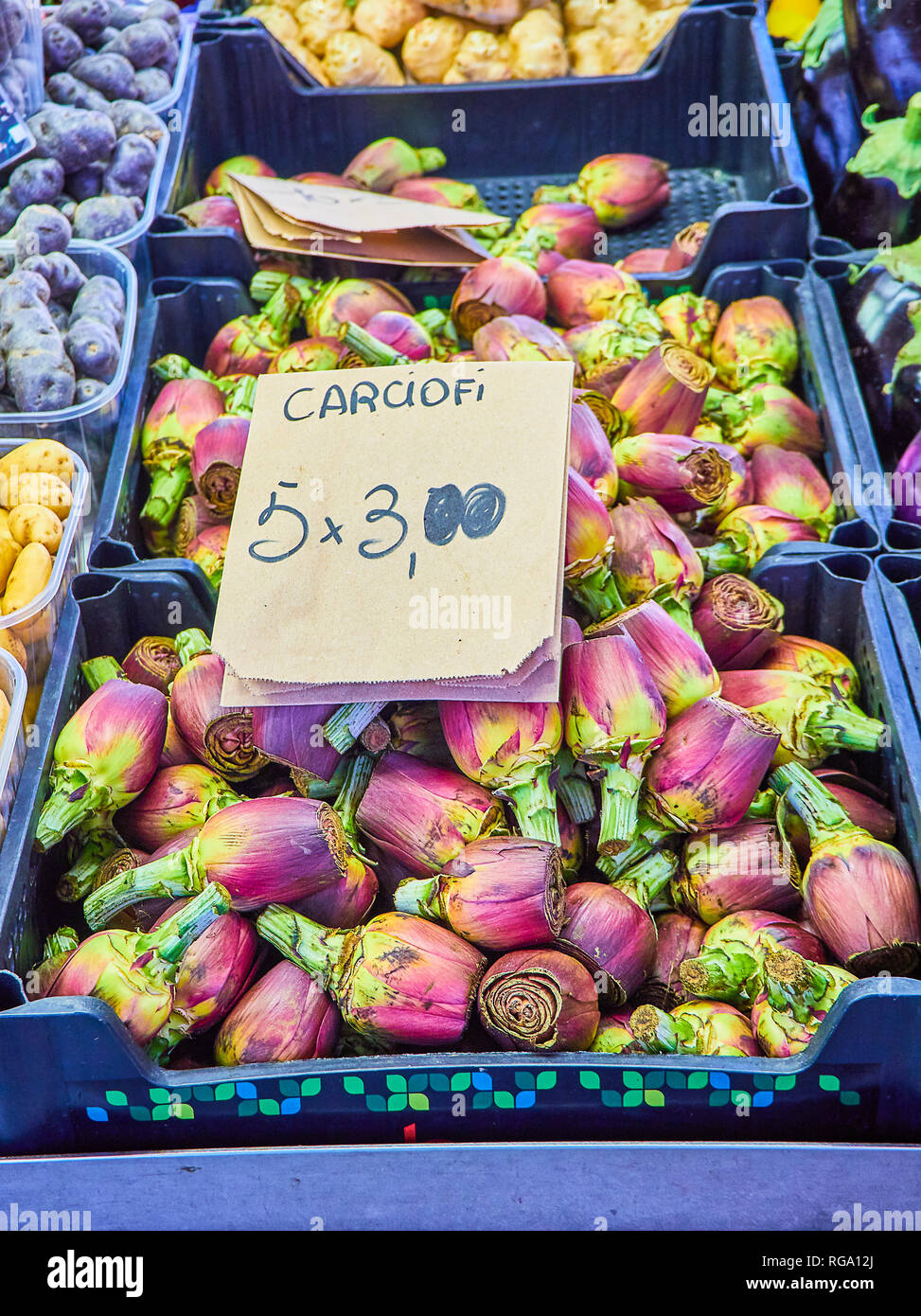 Une boîte d'artichauts violets frais dans un marché avec un cartel en italien montrant le prix. Banque D'Images