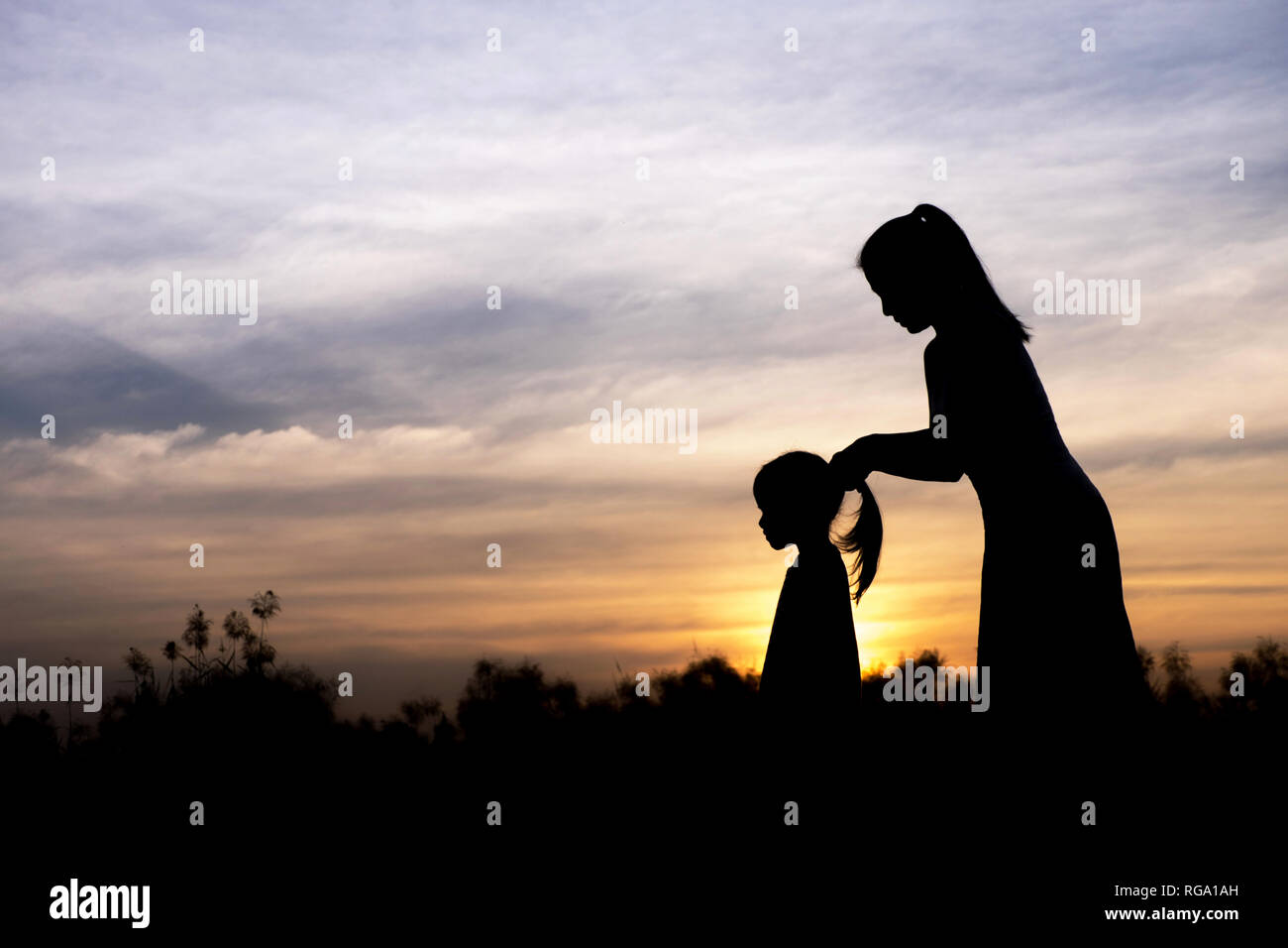 Silhouette de mère et fille au coucher du soleil Banque D'Images