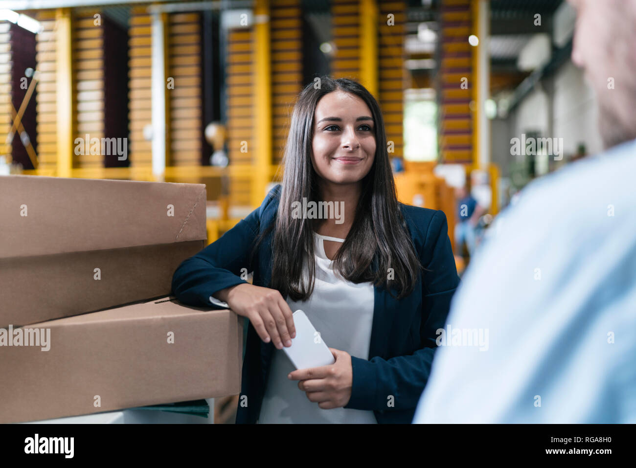 Jeune femme travaillant dans l'entrepôt de distribution, parler aux collègue Banque D'Images