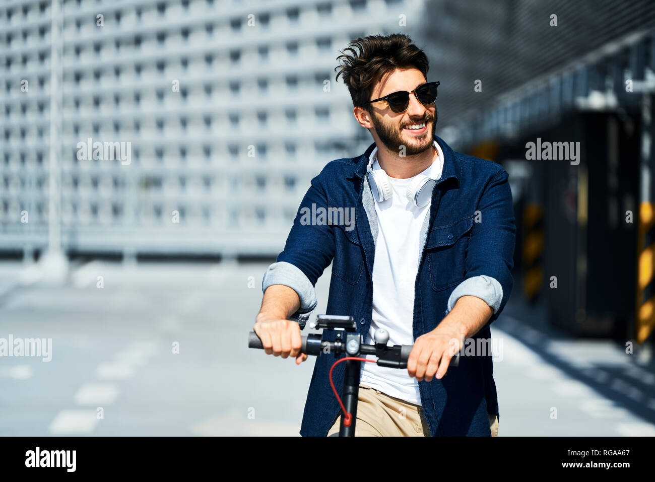 Portrait of smiling man with scooter électrique à l'extérieur Banque D'Images