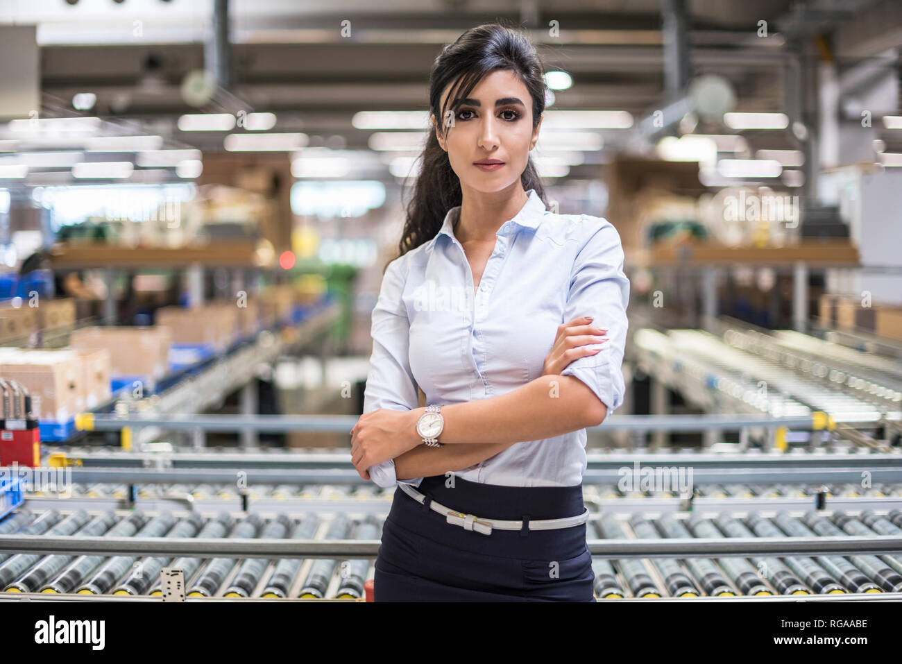 Portrait of smiling woman at conveyor belt in factory Banque D'Images