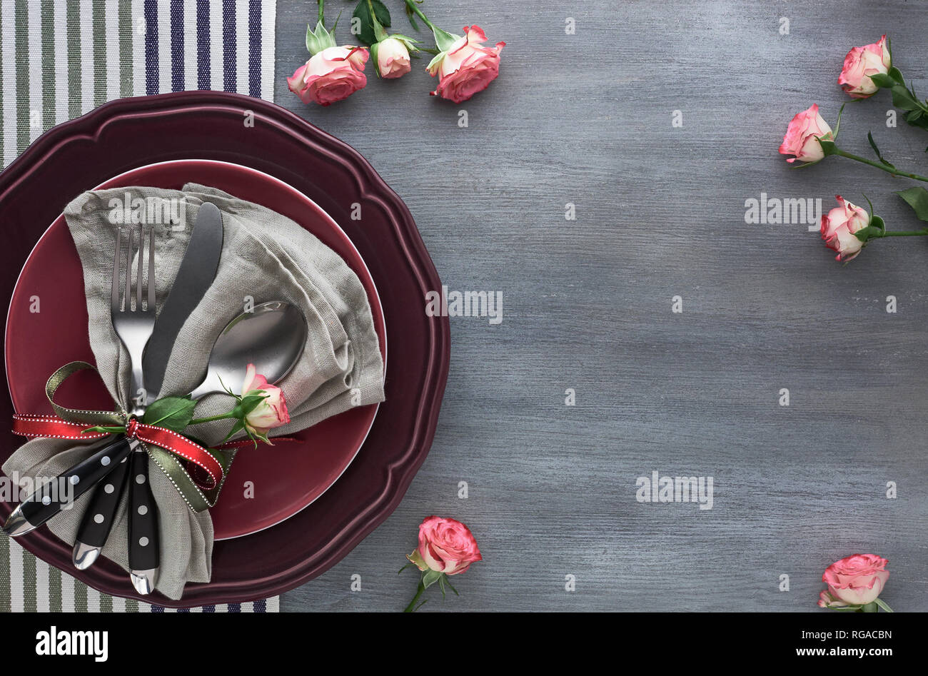 Saint-valentin, anniversaire ou anniversaire table, vue du dessus sur graybackground. Des roses rose, des plaques rouge foncé, serviette et couverts, décoré de ros Banque D'Images