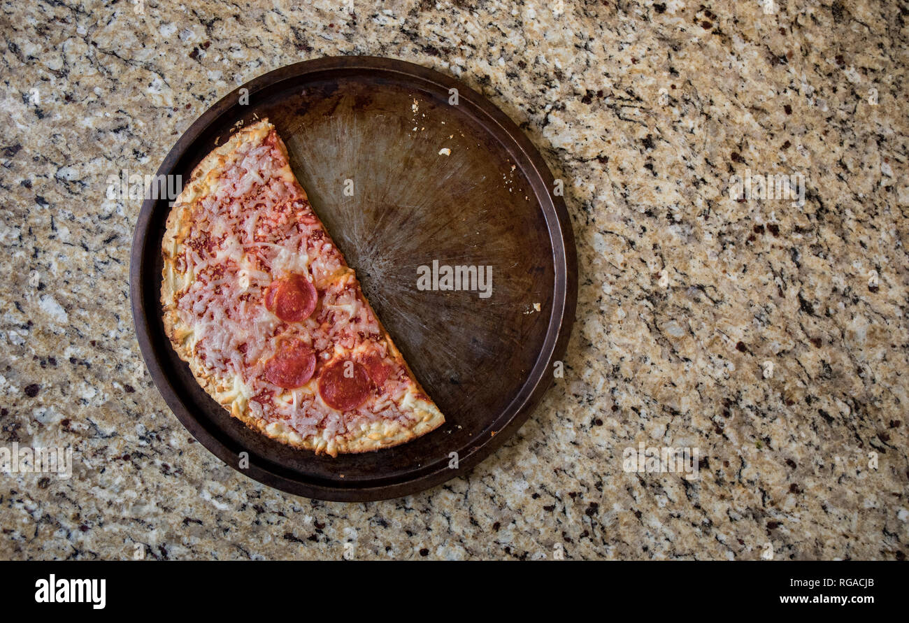 La moitié d'un des restes de pizza surgelée jetée sur le comptoir. Banque D'Images