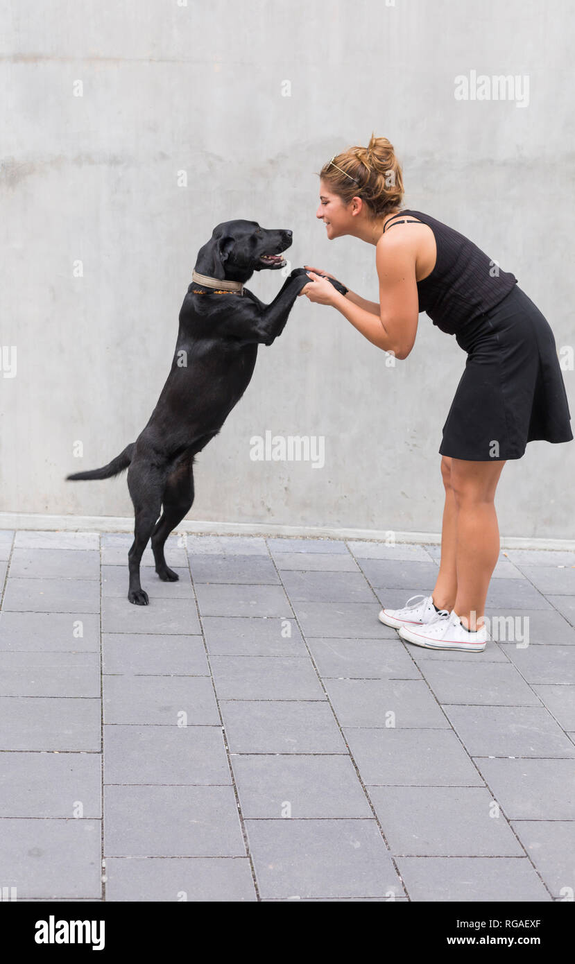 Jeune femme vêtue de noir avec son chien noir Banque D'Images