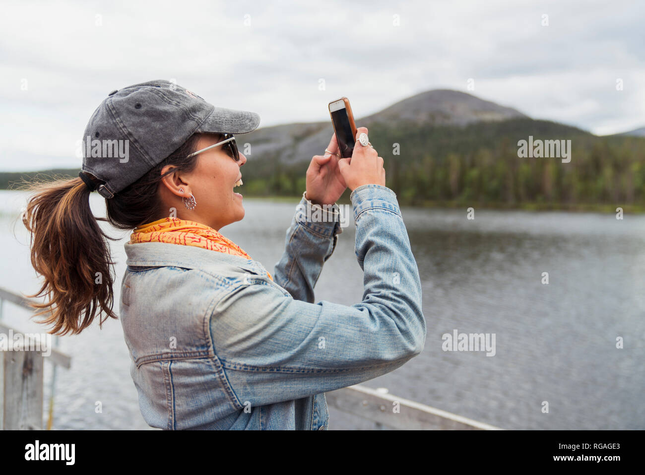 La Finlande, Laponie, happy woman on jetée à un lac en tenant un selfies Banque D'Images