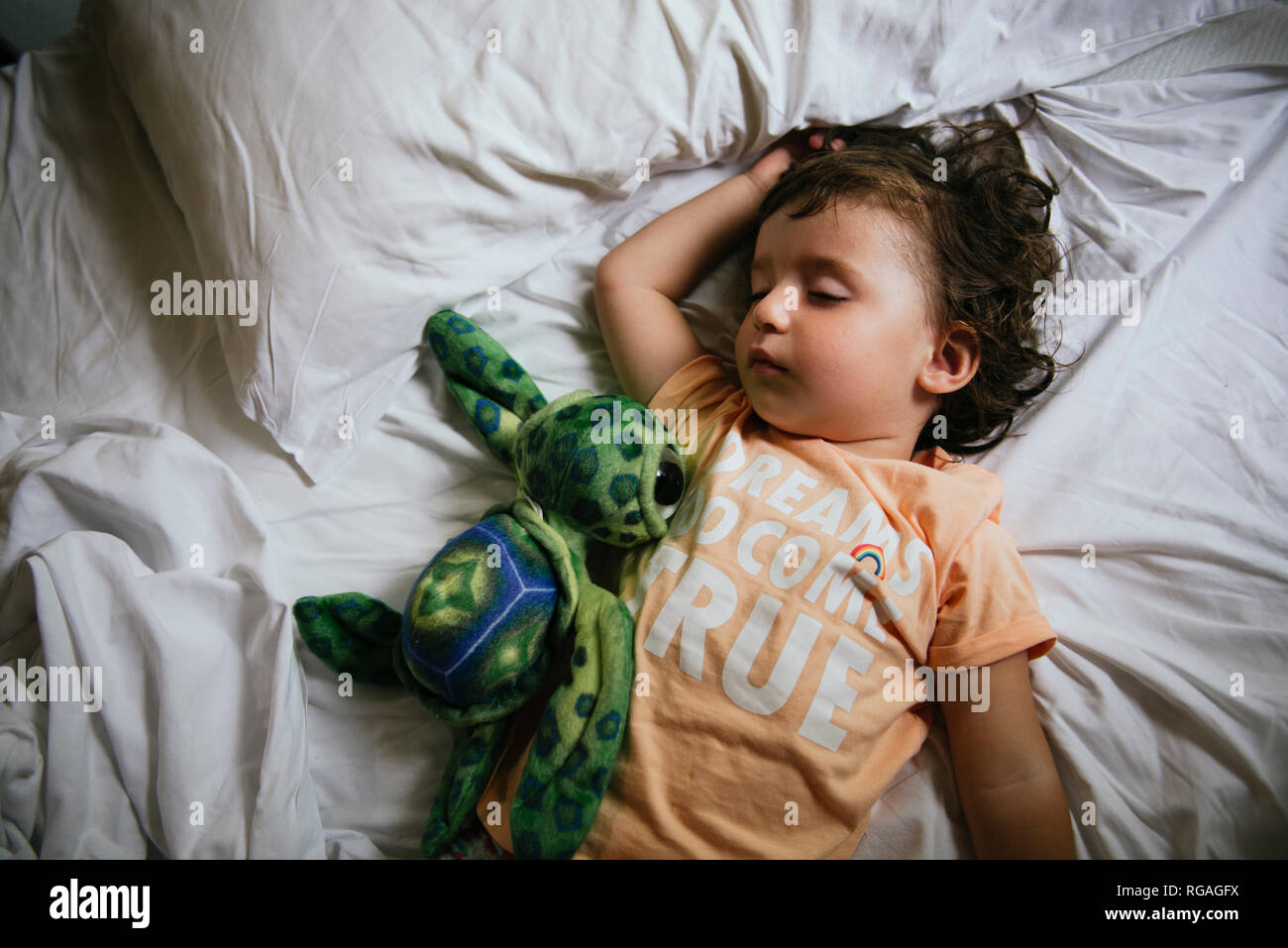 Baby Girl sleeping on bed avec t-shirt message "rêves viennent vrai' Banque D'Images