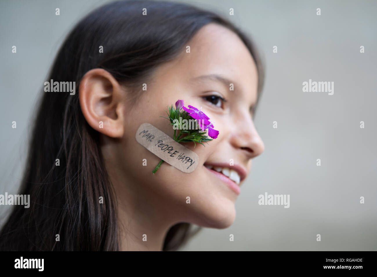 Portrait of smiling girl avec fleur sur sa joue Banque D'Images