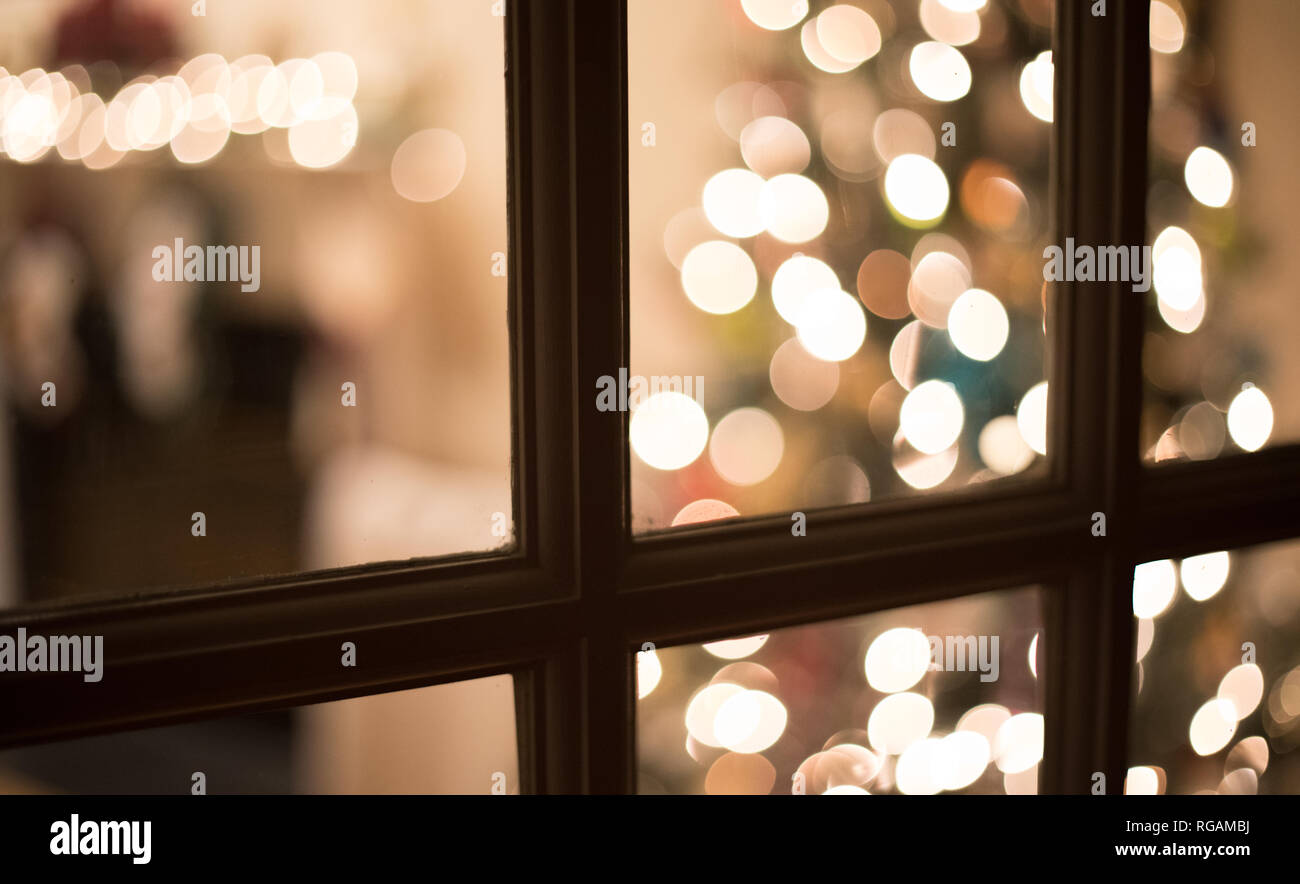 Flou d'une photo à travers une fenêtre, la nuit dans un salon décoré pour Noël. Banque D'Images