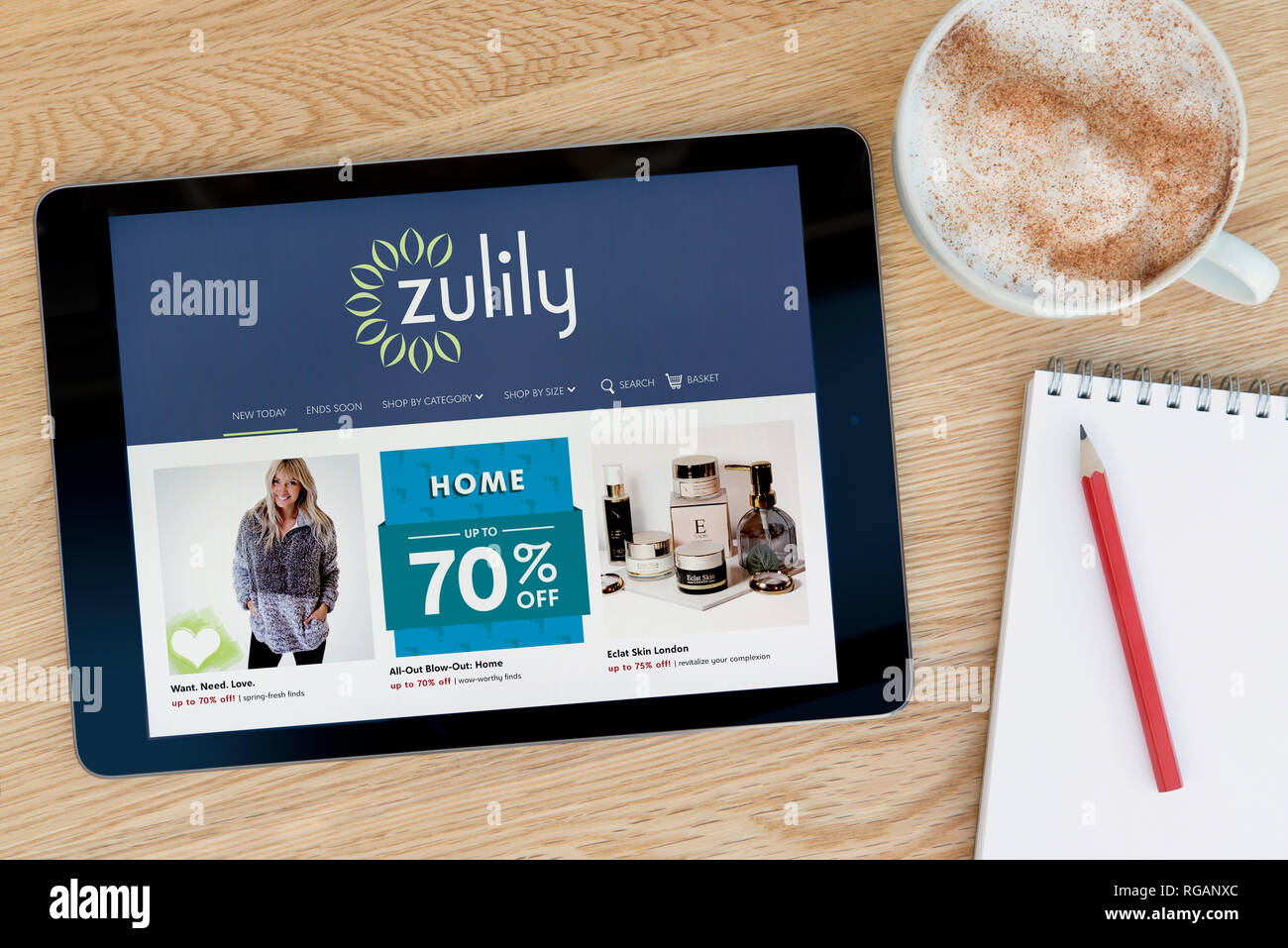 La Zulily site dispose d'un iPad tablet device qui repose sur une table en bois à côté d'un bloc-notes (usage éditorial uniquement). Banque D'Images