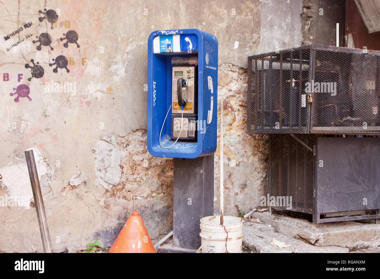 Un public payant bleu ou un téléphone public entouré de graffitis dans un milieu urbain Banque D'Images