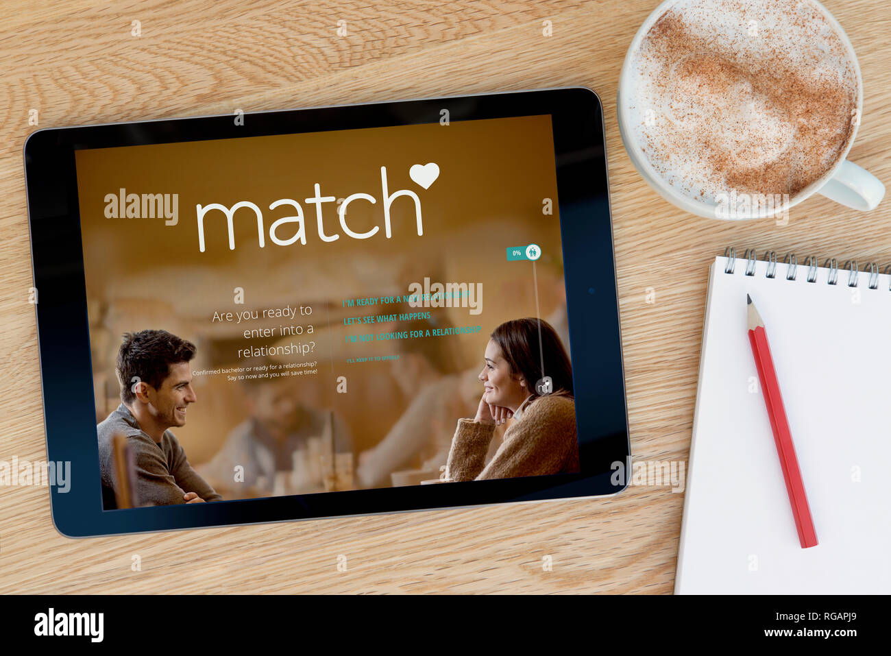 Le site Match.com fonctions sur un iPad tablet device qui repose sur une table en bois à côté d'un bloc-notes (usage éditorial uniquement). Banque D'Images