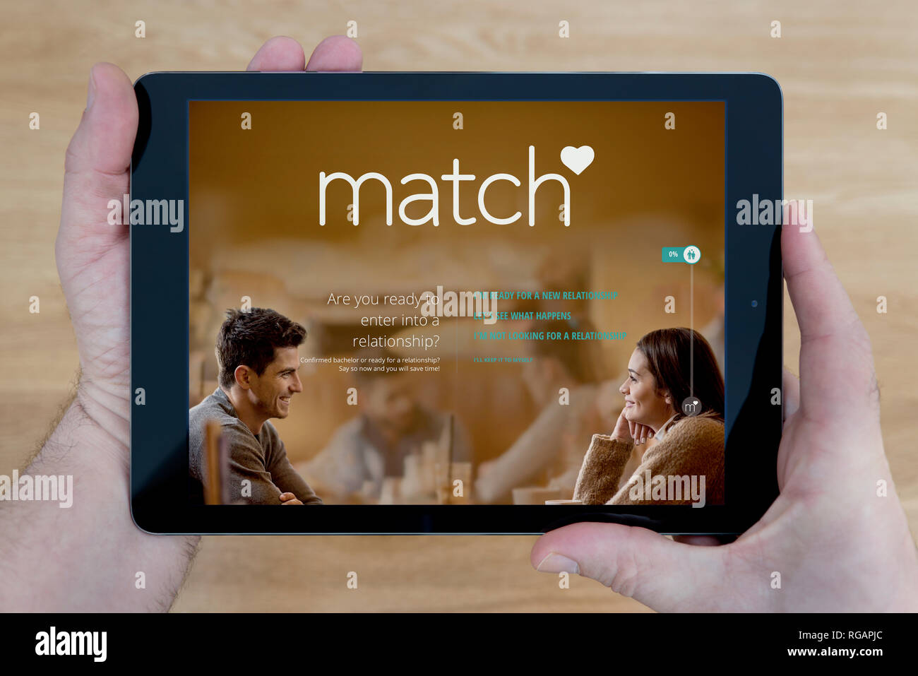 Un homme regarde le site Match.com sur son iPad tablet device, tourné contre une table en bois page contexte (usage éditorial uniquement) Banque D'Images