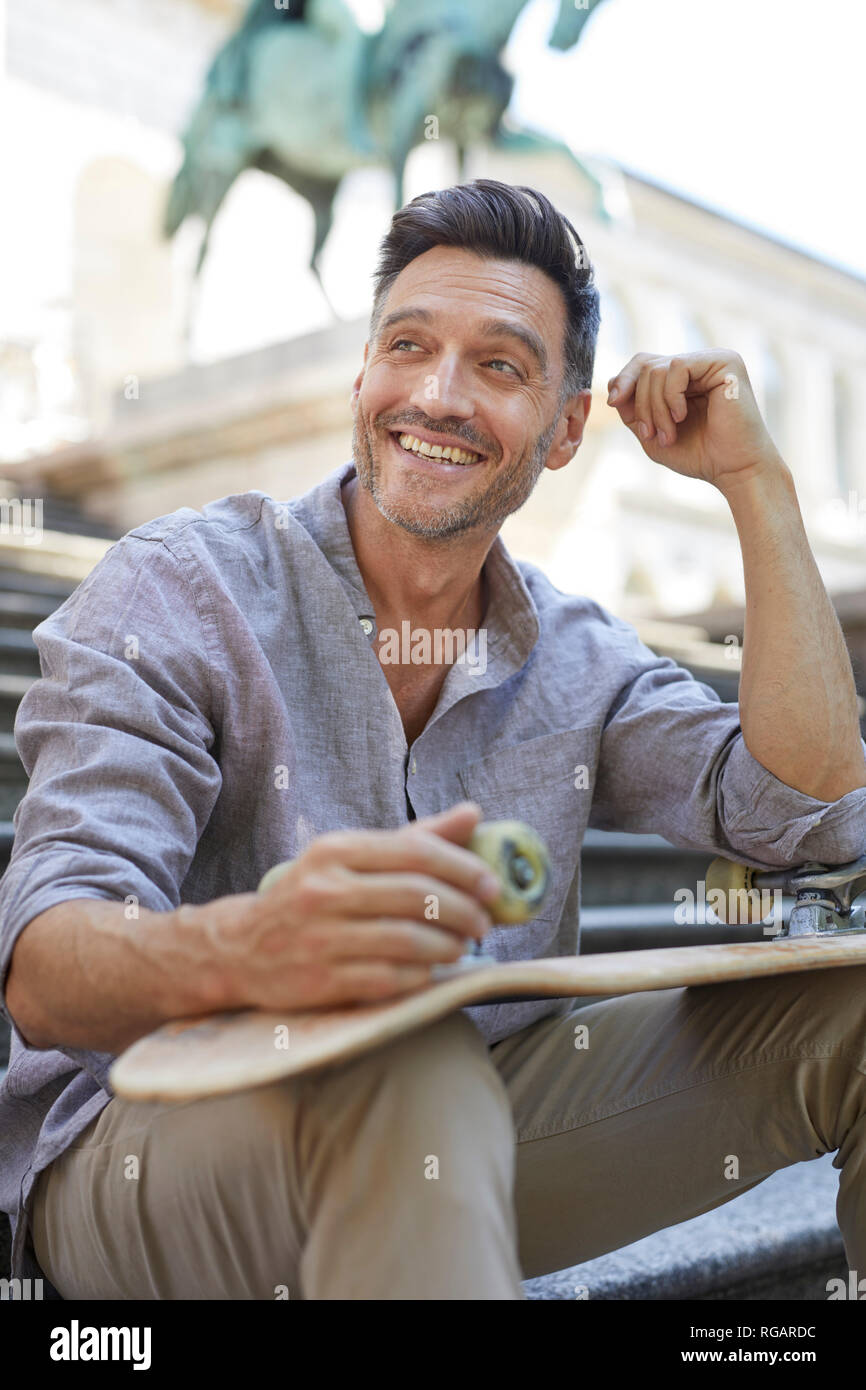 Portrait of laughing man avec skateboard assis sur des escaliers Banque D'Images