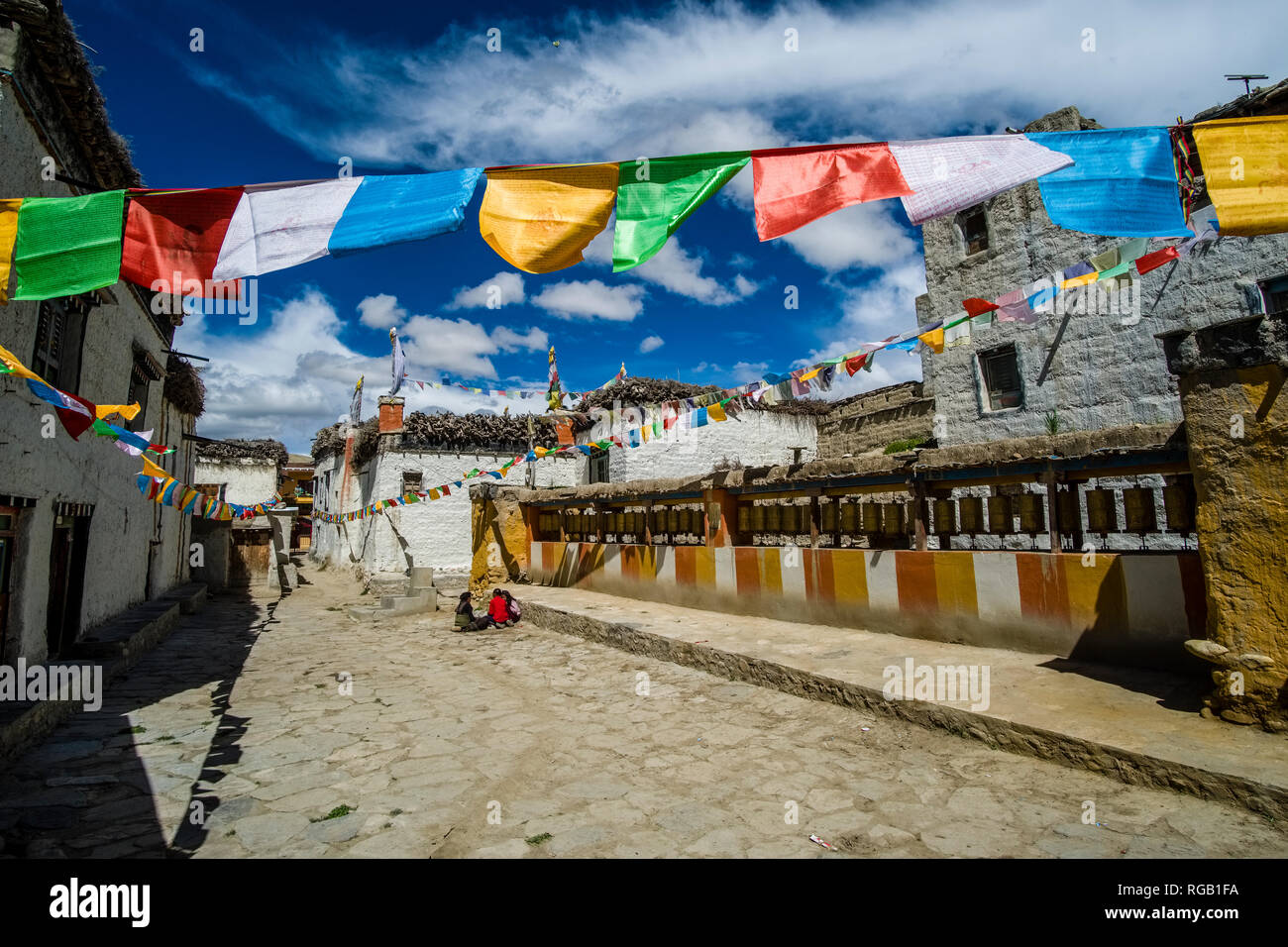 Petite allée avec des maisons traditionnelles, une longue rangée roues de prière et les drapeaux de prières à l'intérieur de la ville close Banque D'Images
