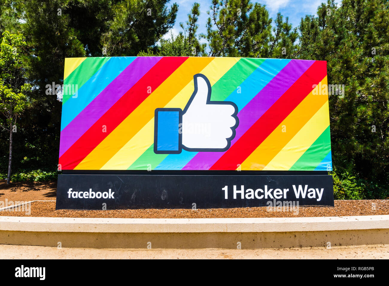 18 juin 2018 Menlo Park / CA / USA - Le bouton Like de Facebook sur un drapeau arc-en-ciel de fond, célébrer le Mois de la fierté LGBT ; entrée de la société. Banque D'Images