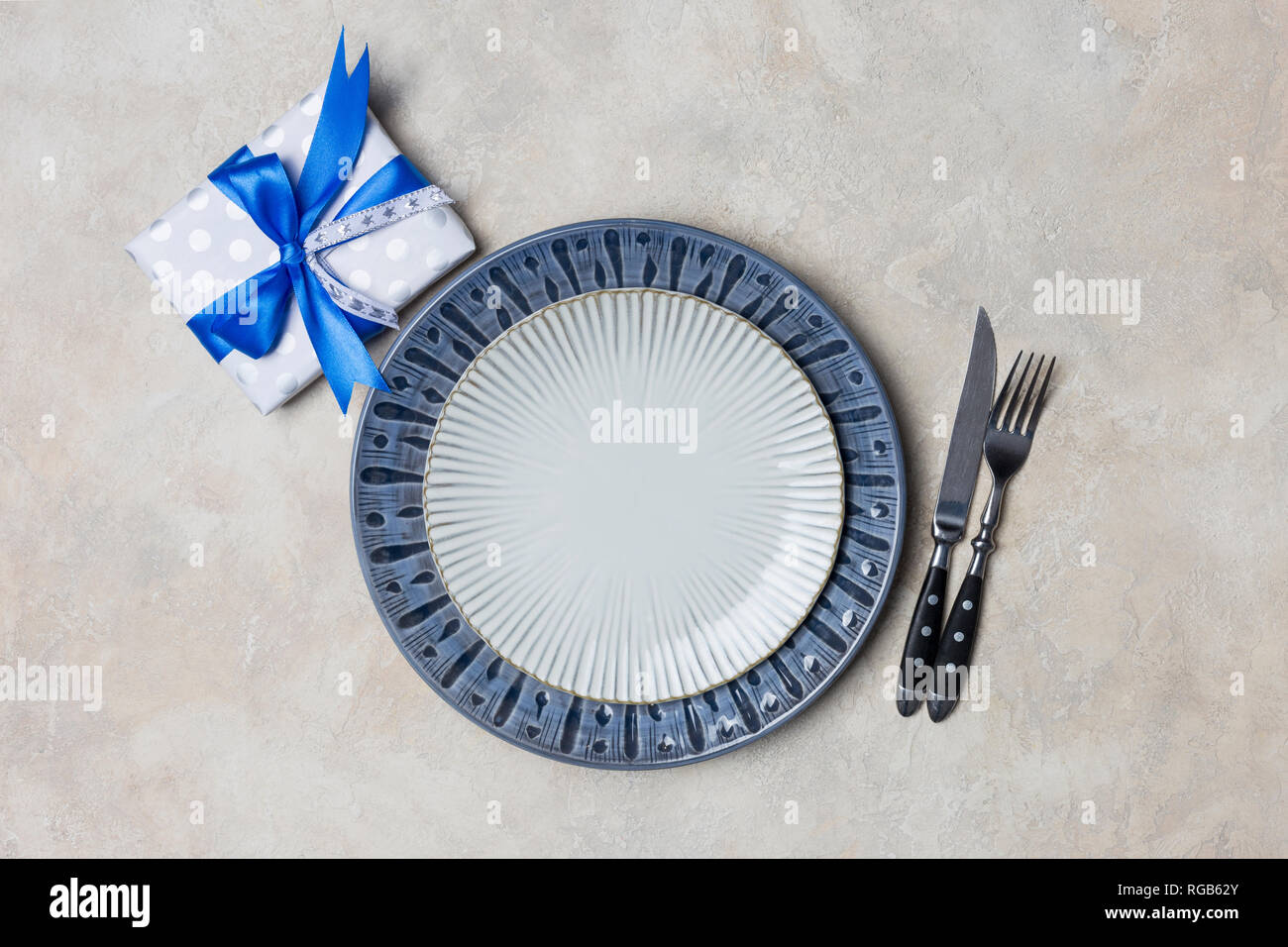 La plaque bleue et blanche avec présent fort pour les hommes avec fourchette et couteau sur fond blanc. Valentine's Day set de table Banque D'Images