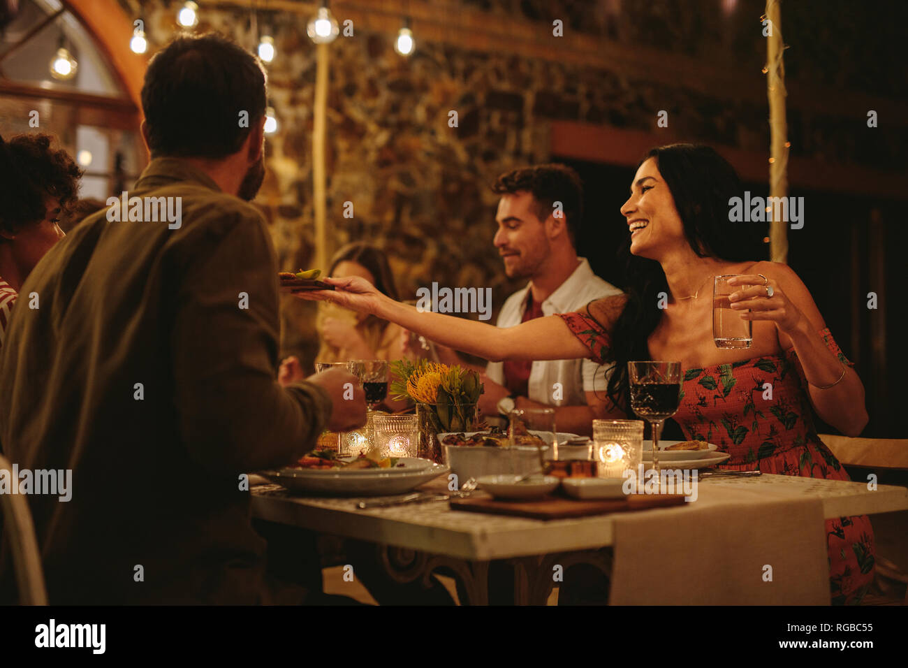 Femme passant de la nourriture à des amis à dîner à l'extérieur. La génération Y qui l'extérieur. Banque D'Images