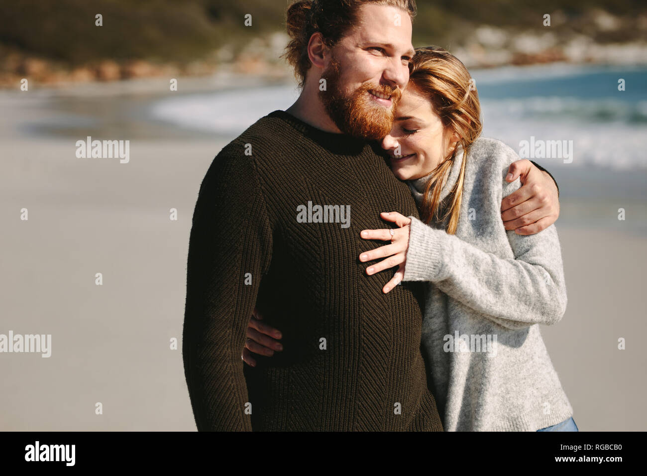 Couple aimant extérieur permanent à la plage. Caucasian woman in her boyfriends armes et souriant à la mer. Banque D'Images