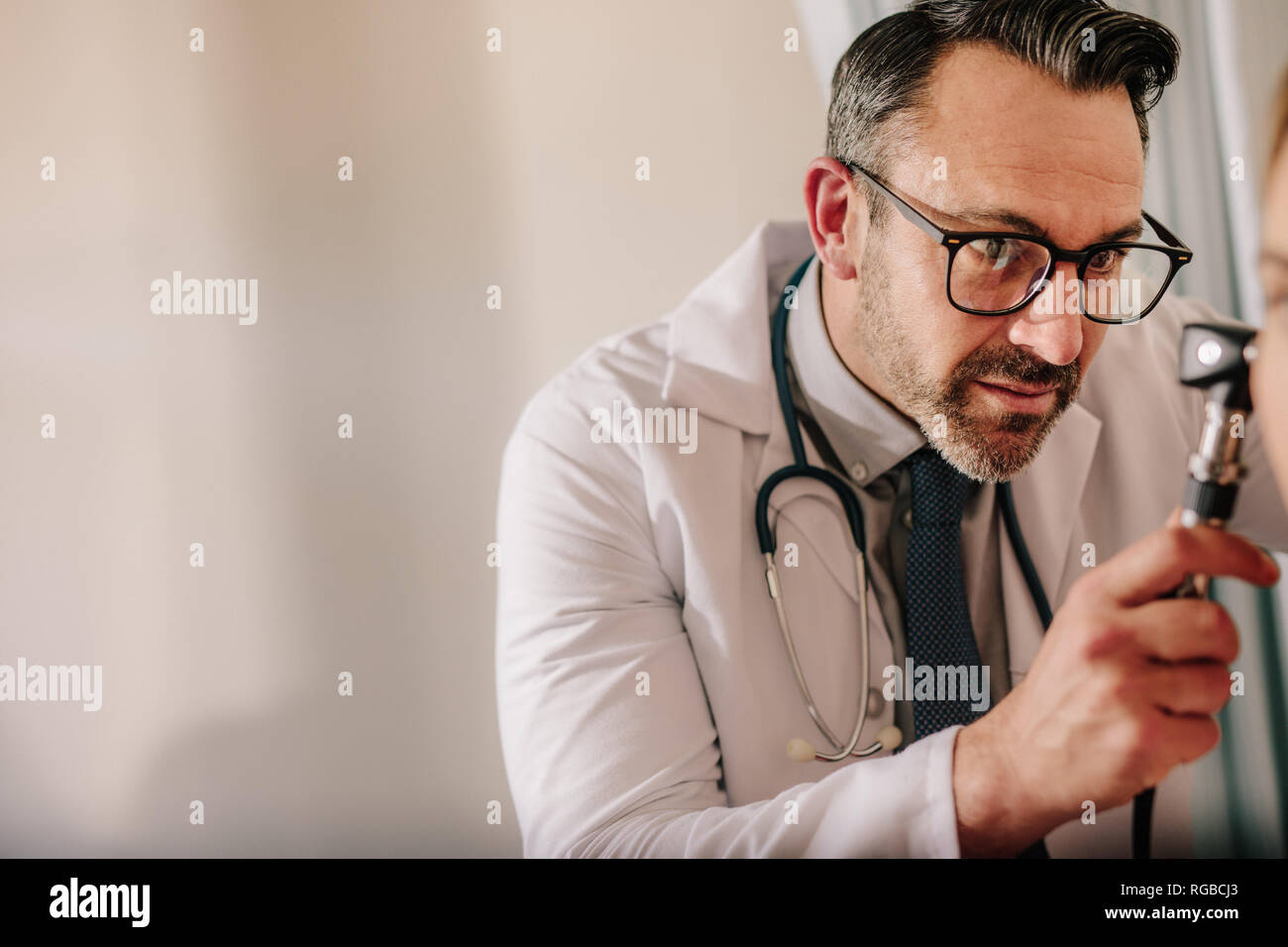 Spécialiste en ORL à la recherche dans l'oreille du patient avec un otoscope à sa clinique. Doctor examining patient's ear avec instrument. Banque D'Images