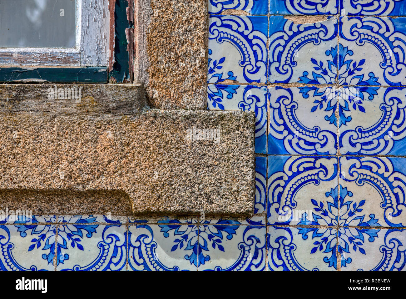 Photographie d'un azulejo bleu peint à la main en céramique émaillée carreaux de mur avec un coin d'une fenêtre en bois sculpté à la main avec un bâti en pierre. Banque D'Images