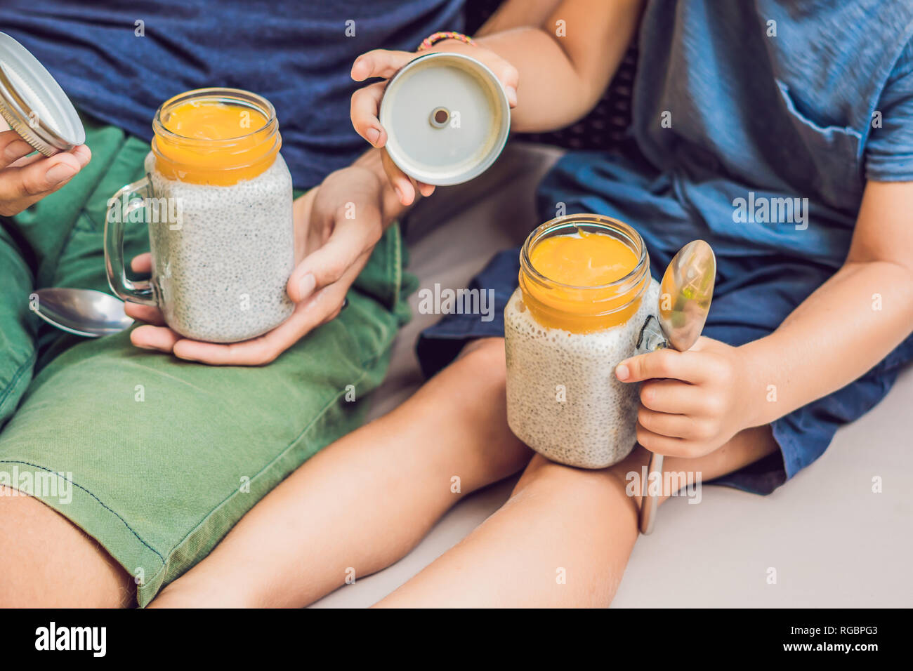Père et fils manger le dessert avec chia seeds et de mangues à la piscine le matin. la saine alimentation, l'alimentation, les régimes végétariens et personnes concept Banque D'Images