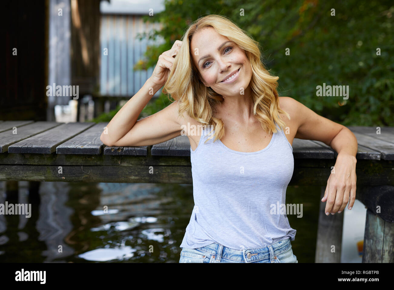 Smiling relaxed woman à jetée en bois sur un lac Banque D'Images