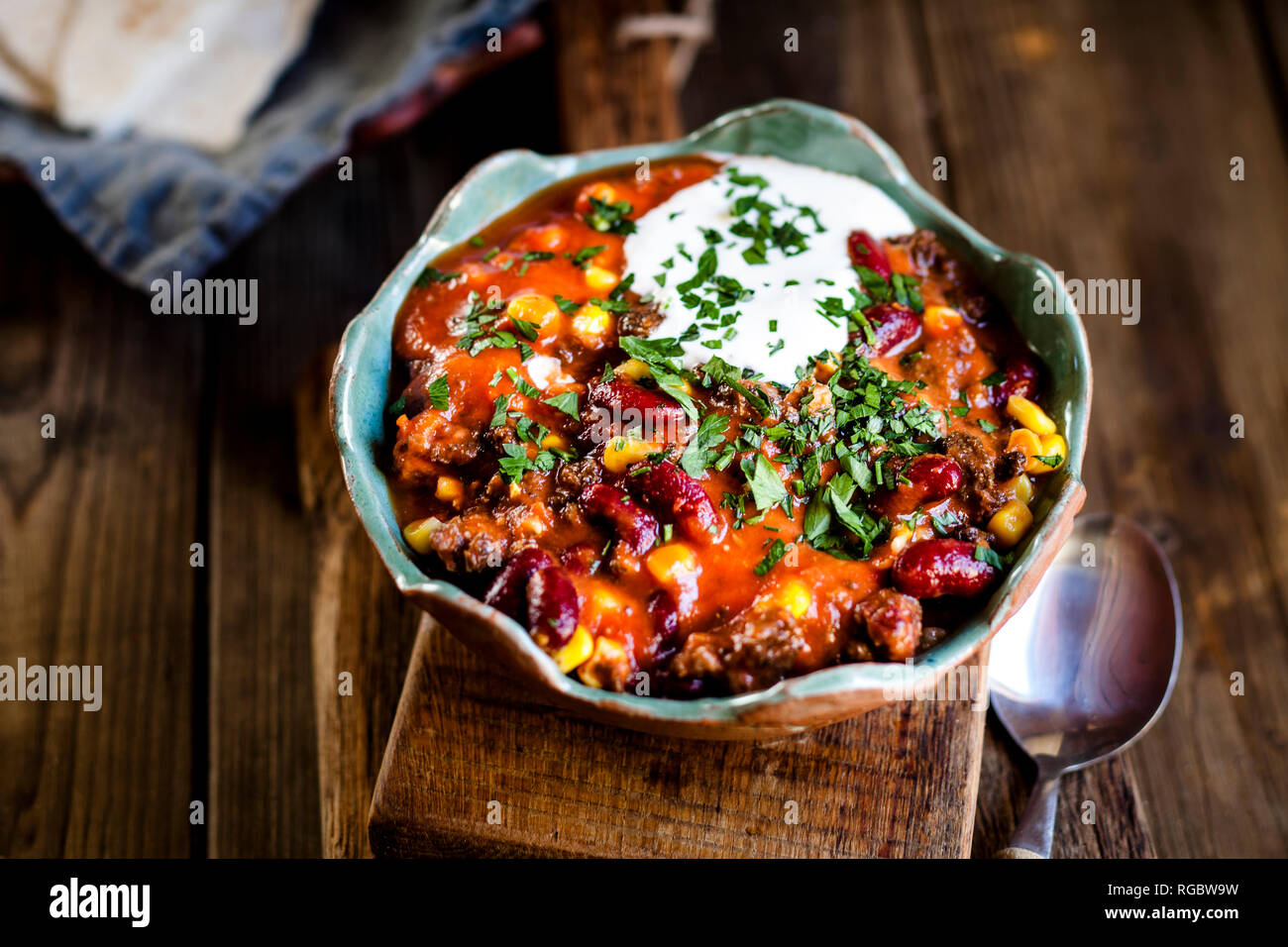 Chili con carne avec des haricots rouges et de maïs, la crème, le persil, le pain tortilla Banque D'Images