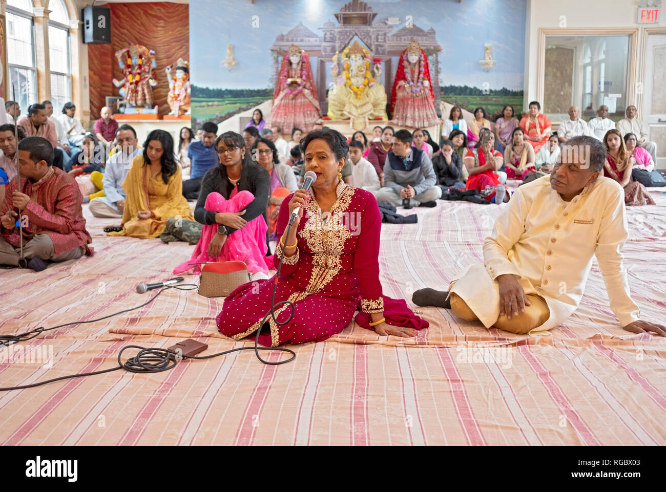 Avec son mari à ses côtés, une femme hindoue chante une prière lors d'une congrégation dans le Queens, New York. Banque D'Images