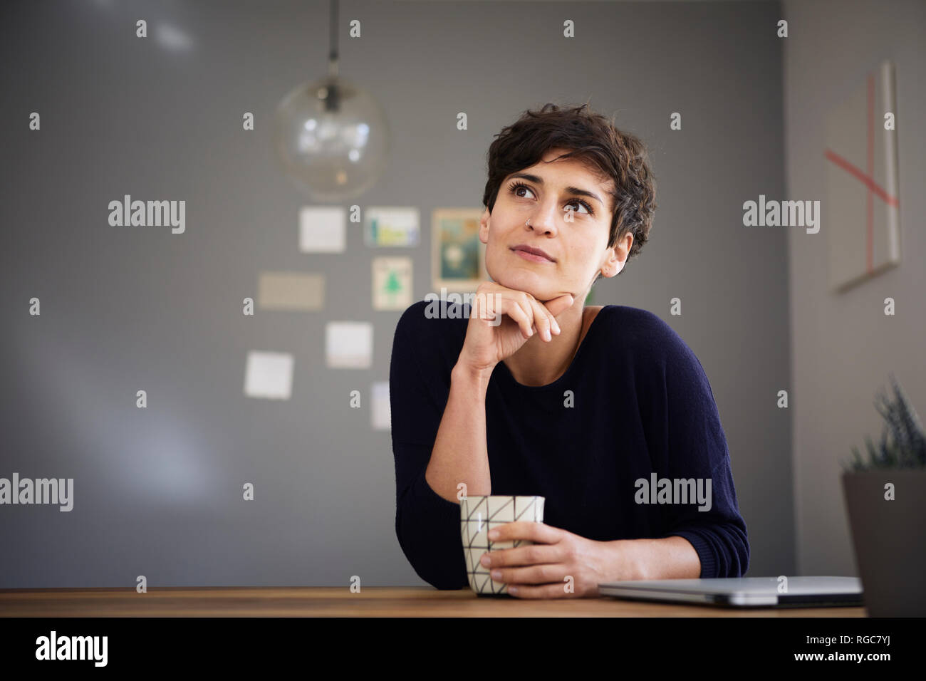 Portrait de femme à la maison assis à table avec tasse de café Banque D'Images
