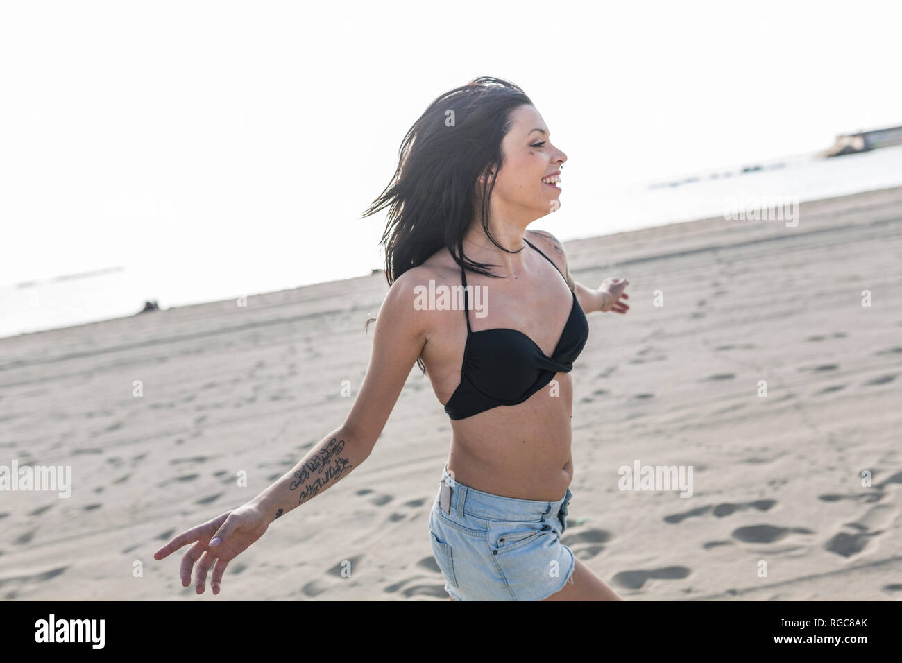 Happy young woman with tattoo et piercing nez s'exécutant sur la plage Banque D'Images