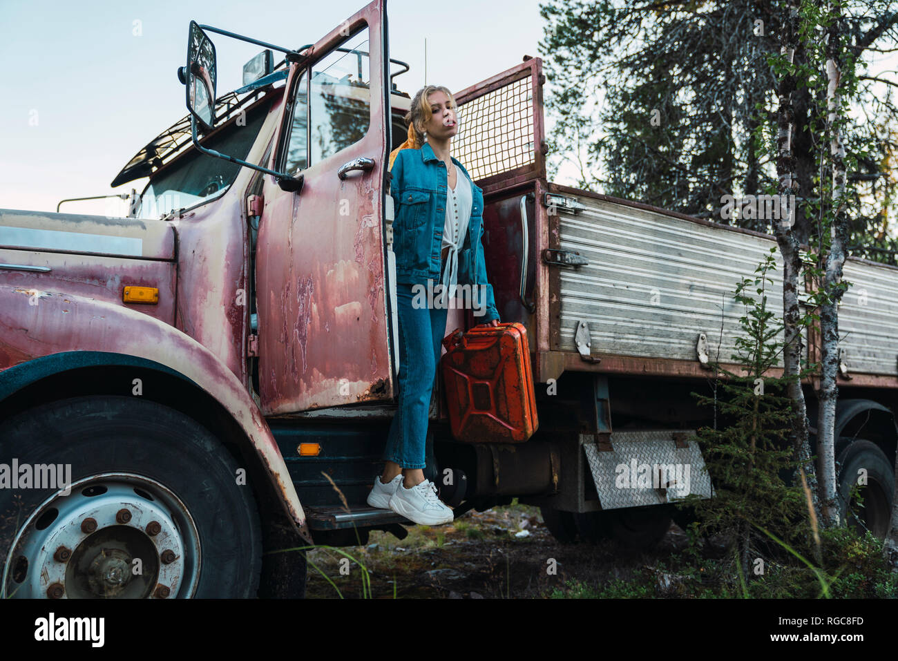 Young woman posing at a broken vintage camion, essence peut maintenant Banque D'Images