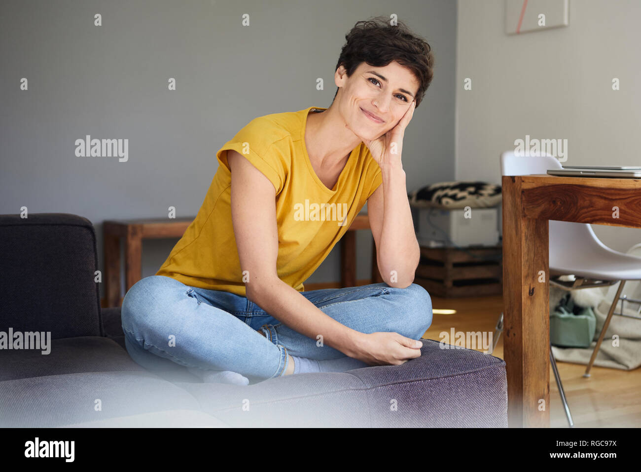 Portrait of smiling woman sitting on sofa at home Banque D'Images