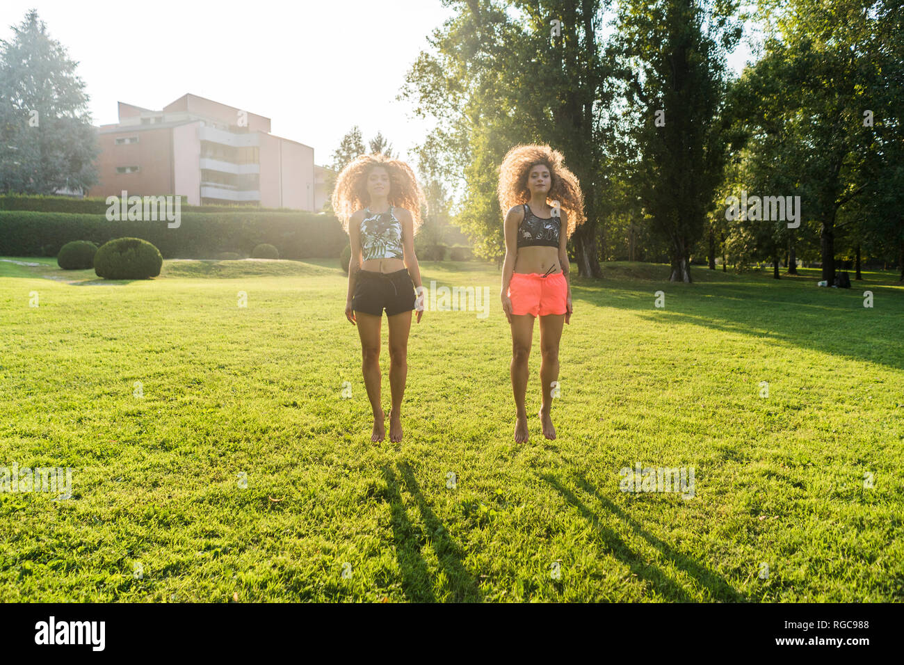 Twin Sisters hopping pieds nus sur un pré à rétro-éclairage Banque D'Images