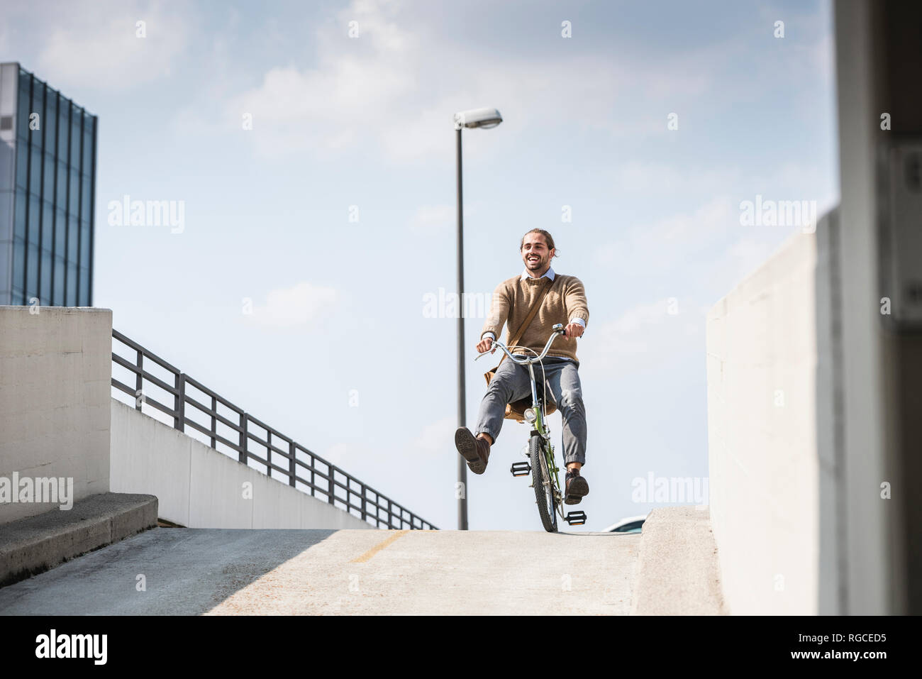 Laughing businessman riding en bas d'une rampe sur son vélo Banque D'Images