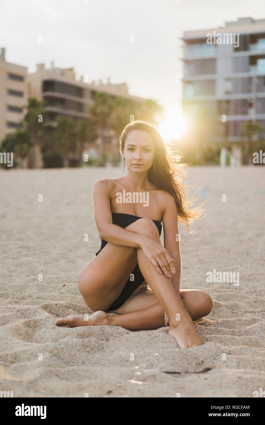 Portrait de la belle jeune femme assise sur la plage au coucher du soleil Banque D'Images