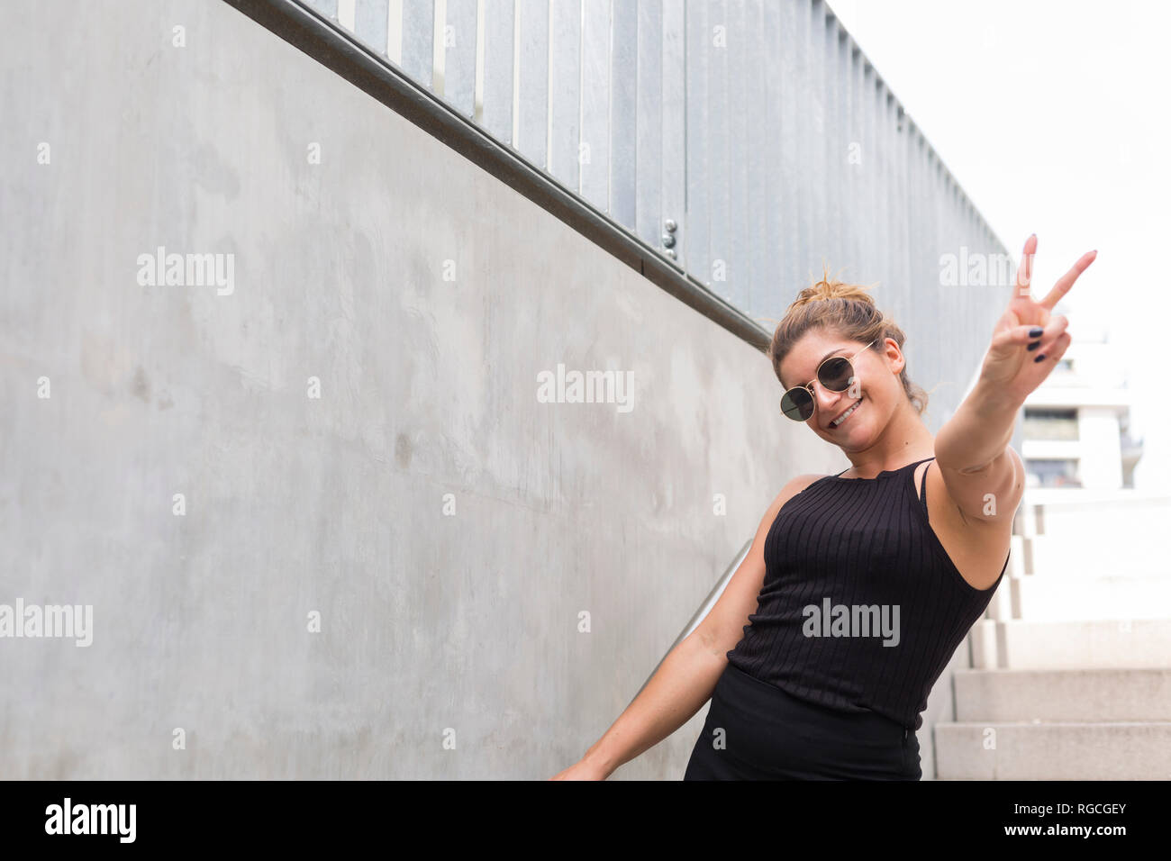 Portrait of happy young woman dressed in black montrant la victoire Banque D'Images