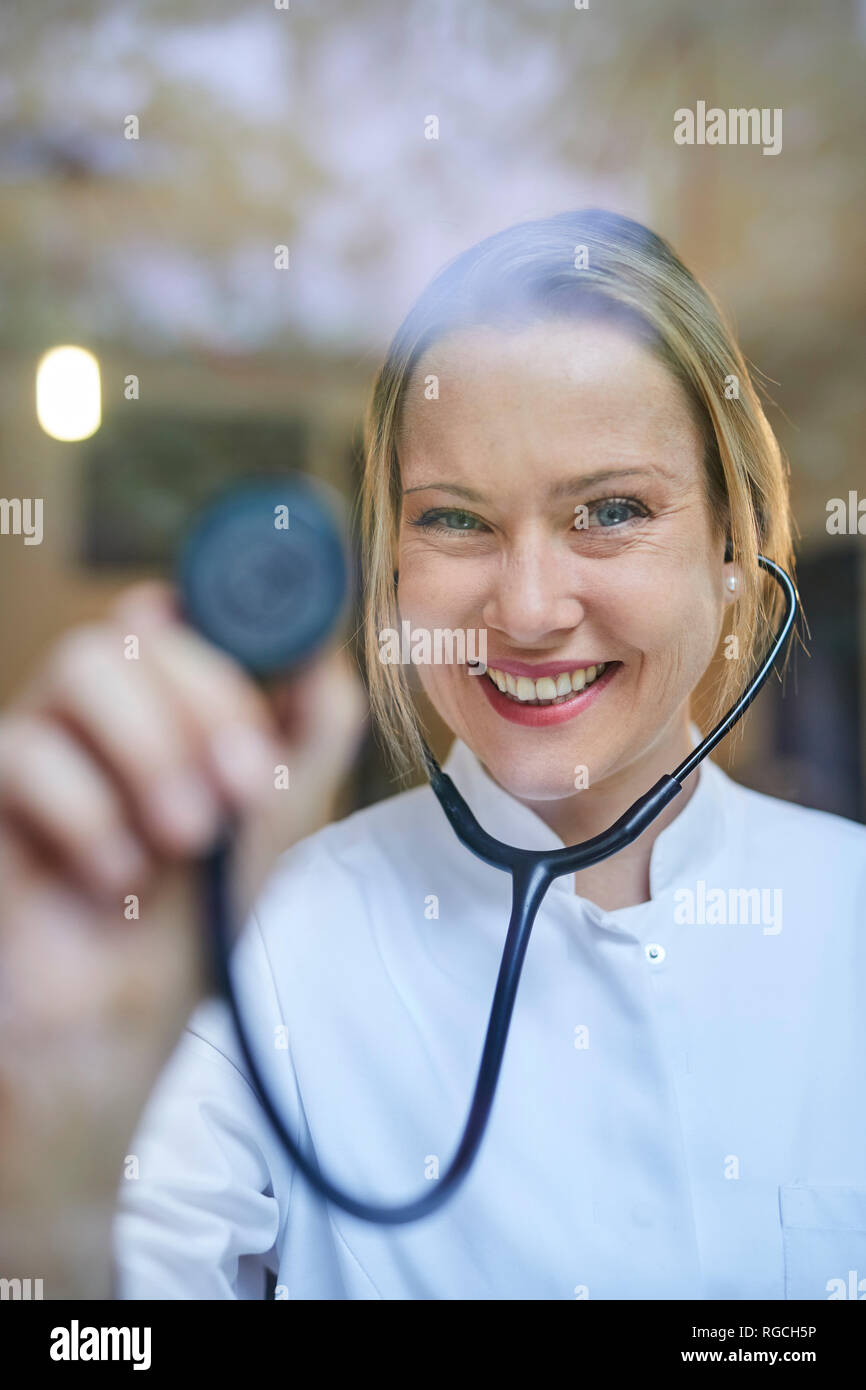 Portrait of smiling female doctor holding stethoscope Banque D'Images