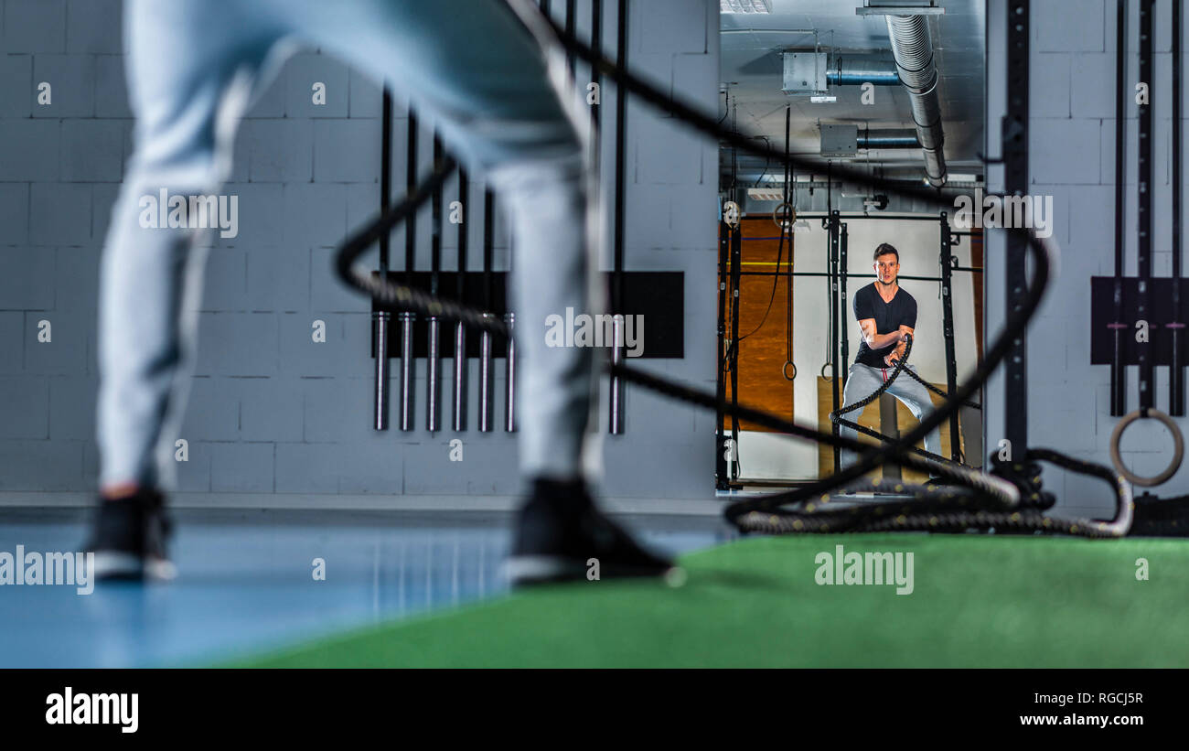 Jeune homme athlétique s'exercer avec des cordes à la salle de sport de combat Banque D'Images