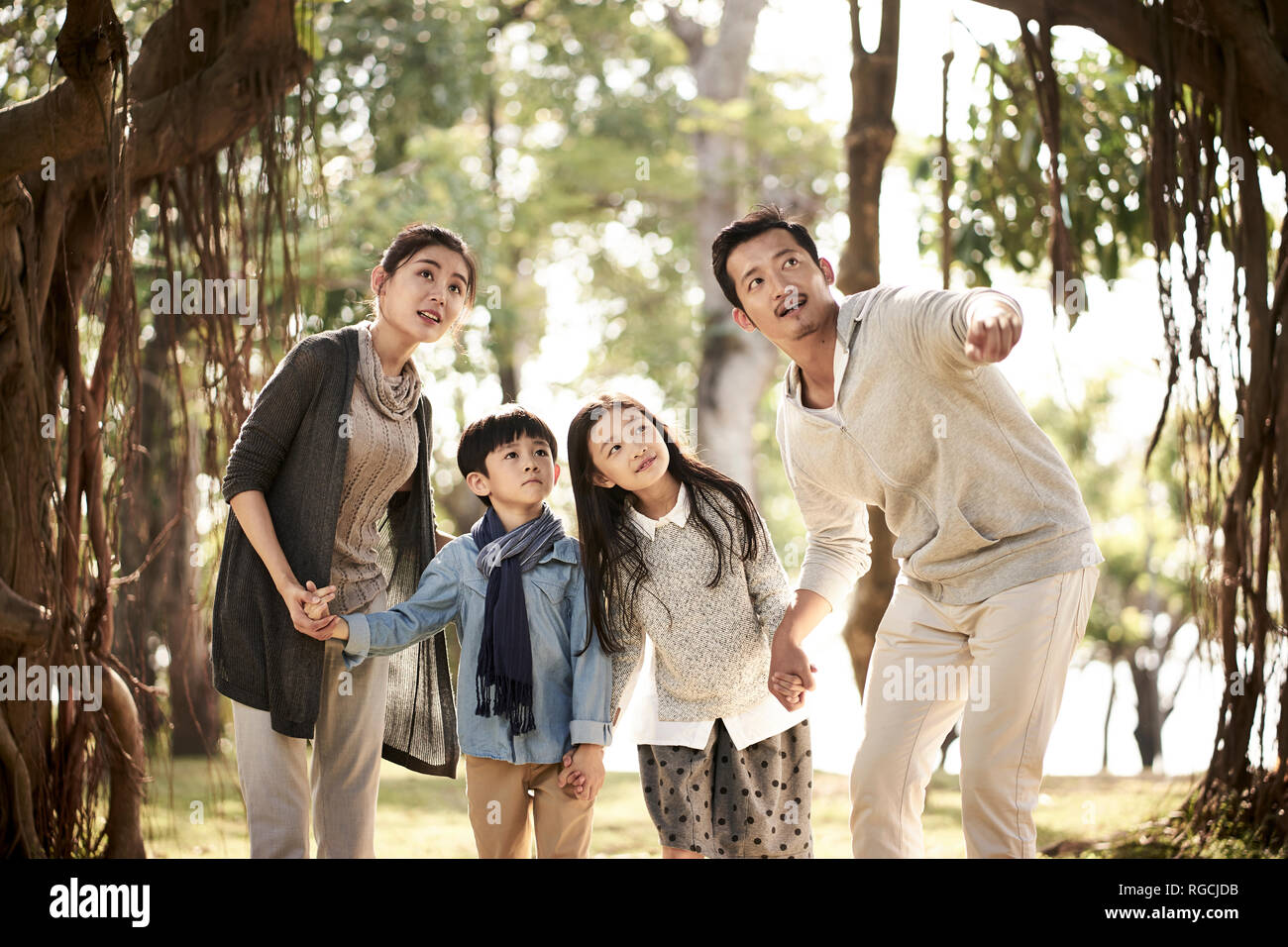 La famille asiatique avec deux enfants s'amusant à explorer les bois dans un parc. Banque D'Images
