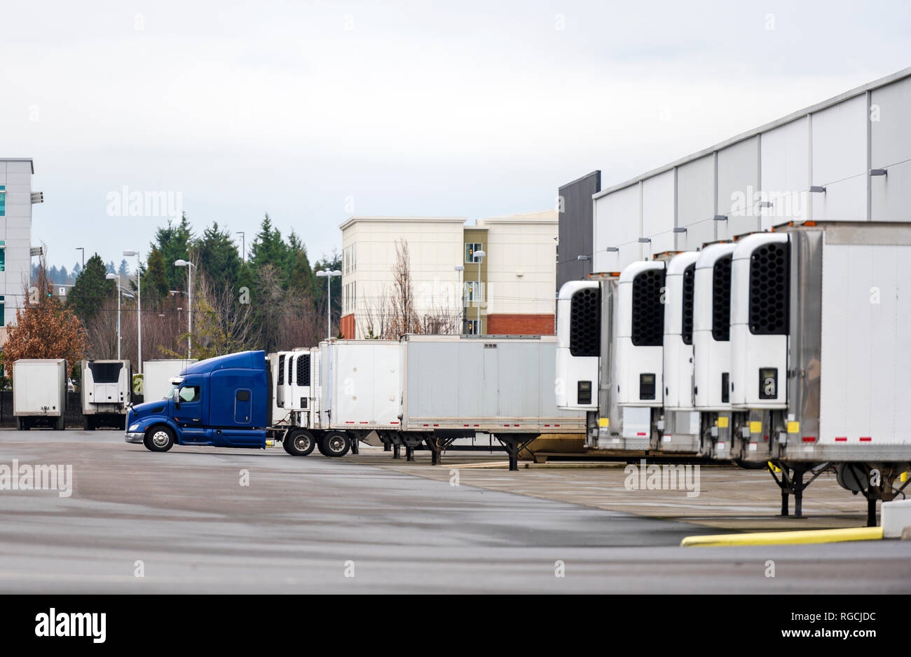 Gros Camion Camion semi bleu et les semi-remorques frigorifiques debout dans ligne de quai de l'entrepôt pour le chargement et le déchargement de la cargaison commerciale et formation continue rendez-vous Banque D'Images