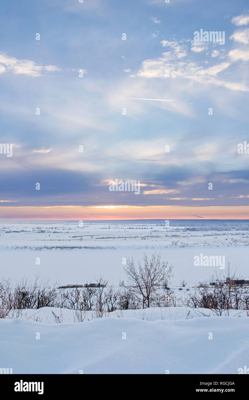 Coucher du soleil hiver Scène : Frosty Landscape avec Snowdrift et arbres sur le premier plan et ciel tranquille Banque D'Images