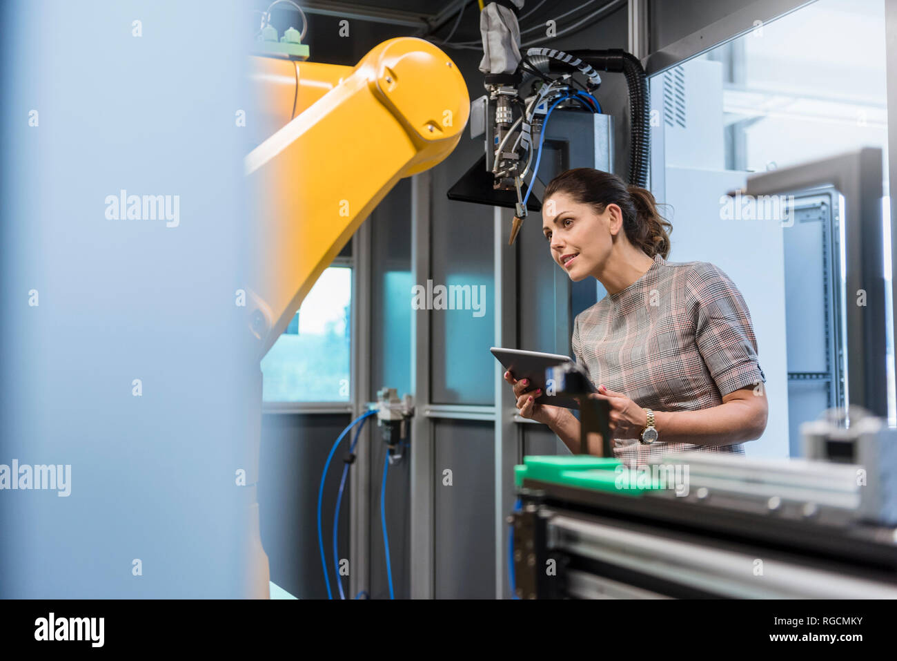 Businesswoman contrôler un robot industriel dans une entreprise de haute technologie Banque D'Images