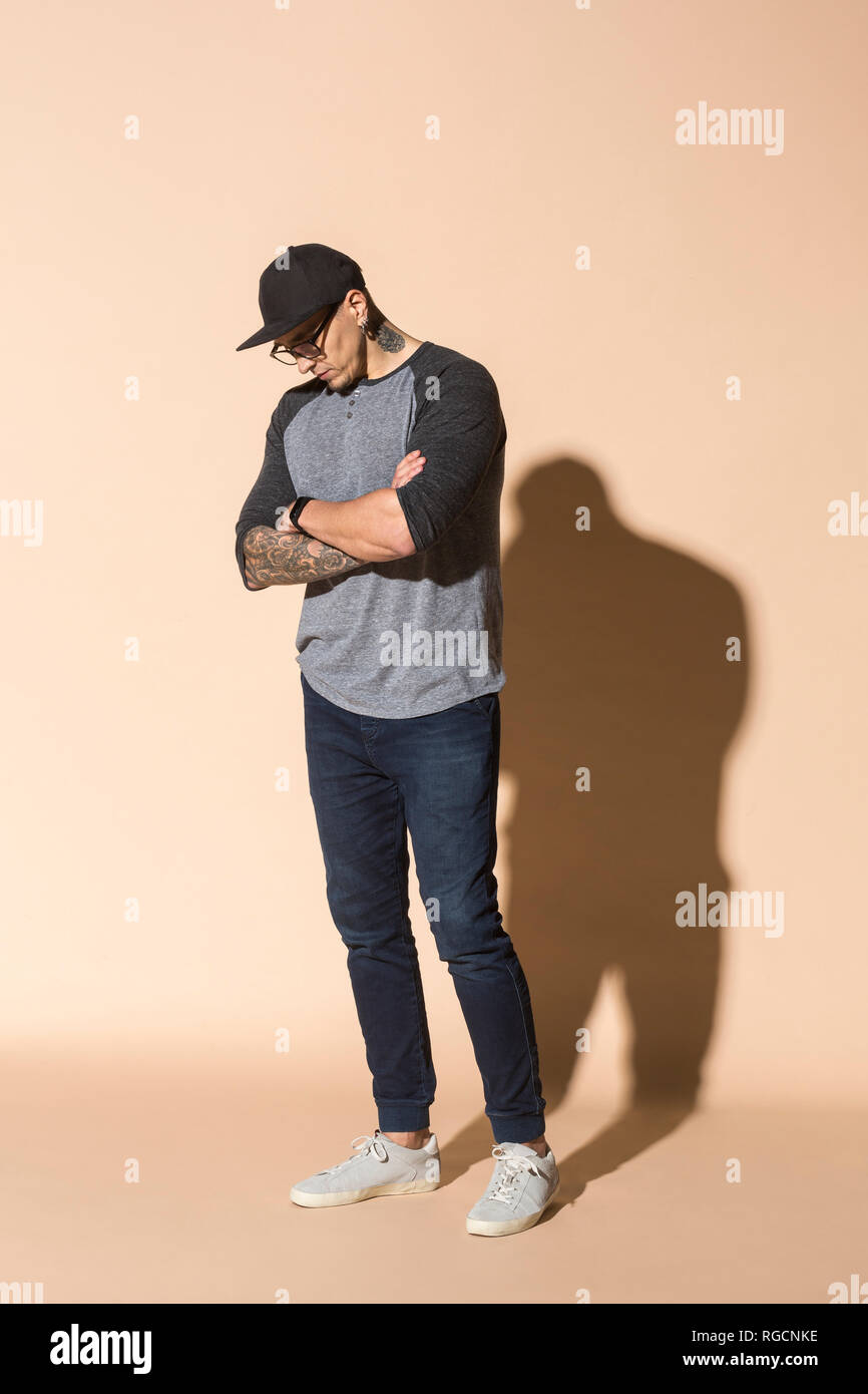 Tattooed man wearing basecap et verres à la bas Banque D'Images