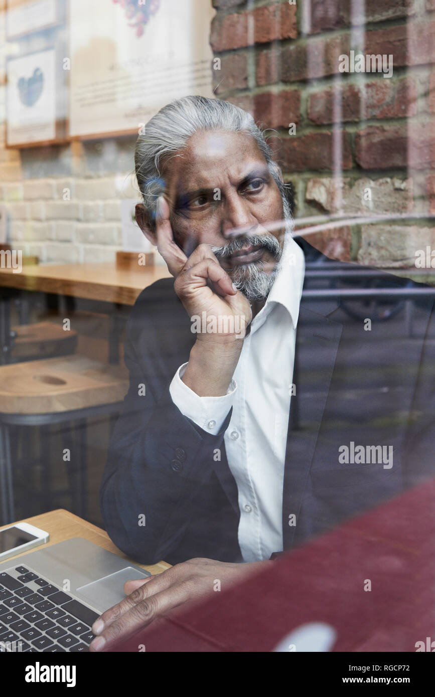 Portrait of smiling senior businessman dans un café à la fenêtre de Banque D'Images