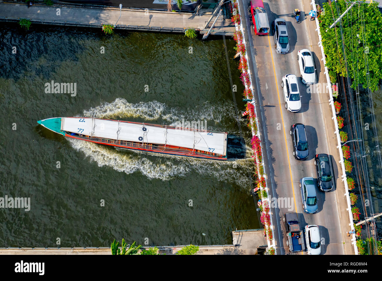 Vue aérienne de voitures sur un pont traversant un canal de Bangkok et de navette bateau passant sous. Banque D'Images