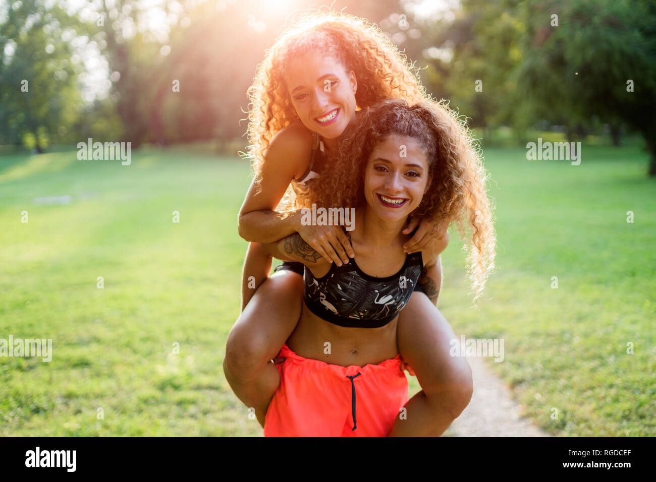 Portrait of smiling young woman giving sa soeur jumelle un piggyback ride Banque D'Images