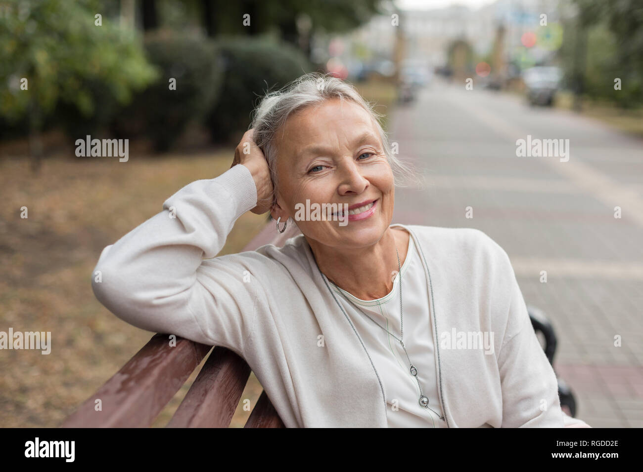 Portrait of smiling senior woman relaxing on a bench Banque D'Images